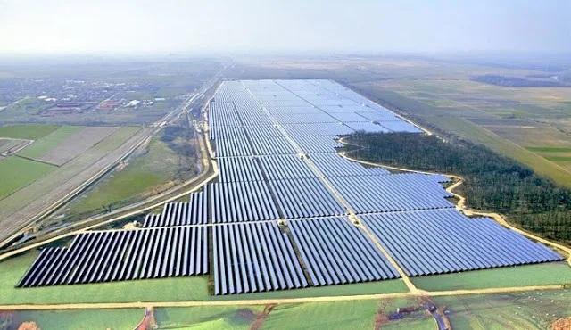 Vista aérea de uma usina solar fotovoltaica: dezenas de fileiras de módulos cobrindo uma área equivalente a várias quadras, ambiente onde o equipamento automatizado pela Taquionica opera